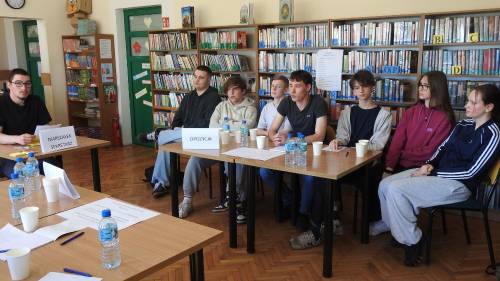 Grupa uczniów siedzi przy stole i prowadzi dyskusję