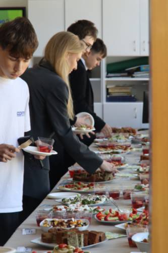 Uczniowie i goście nakładają sobie na talerz przekąski