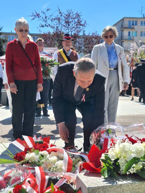 Uczestnicy uroczystości składają kwiaty pod pomnikiem Nike