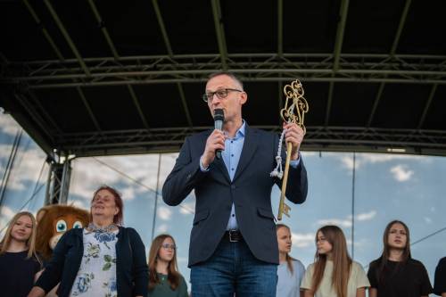 Burmistrz Pruszcza stoi z mikrofonem i dużym kluczem