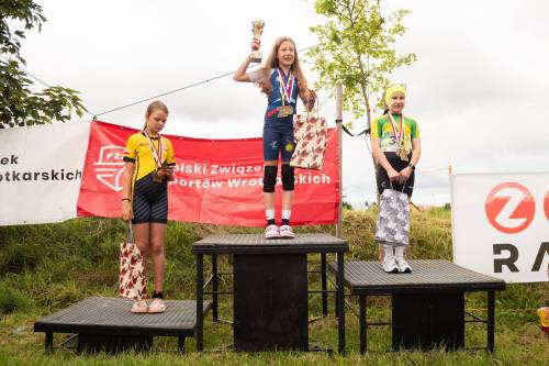 Trzy dziewczyny stoją na podium z nagrodami i medalami
