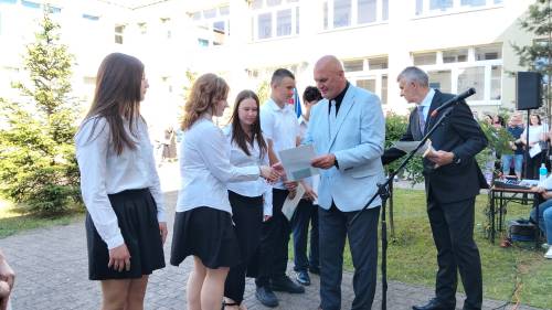 Dyrektor szkoły wręcza uczniom dyplomy