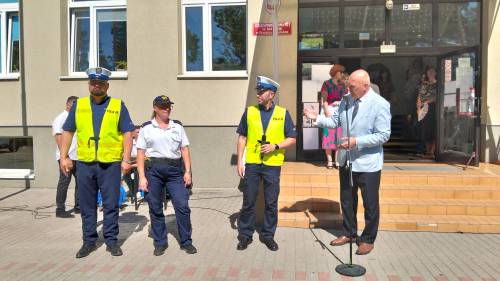 Dwóch policjantów, strażniczka miejska i dyrektor szkoły stoją przed szkołą