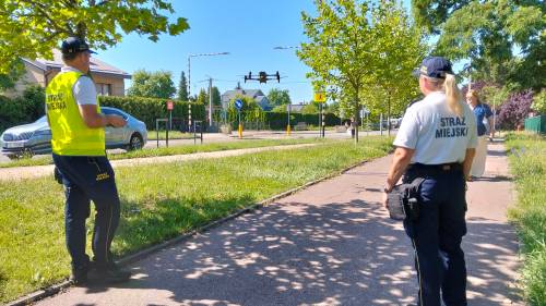 Strażnik i strażniczka miejska z dronem stoją na ścieżce