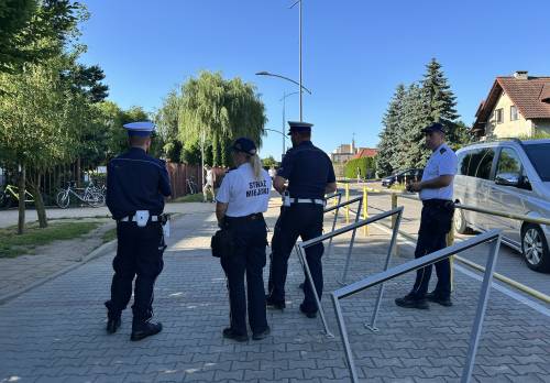 Policjanci i strażnicy miejscy stoją przed szkołą