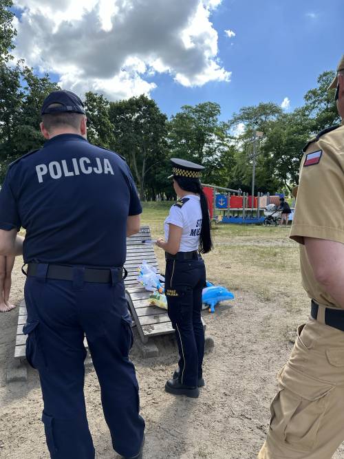 Zbliżenie od tyłu na policjanta, strażniczkę miejską na plaży
