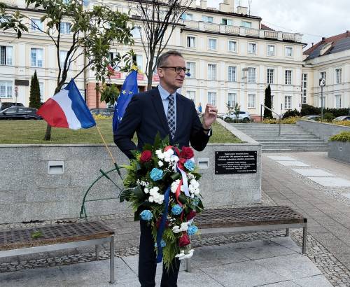 Burmistrz Pruszcza Gdańskiego z kwiatami w ręku stoi przy tablicy pamiątkowej