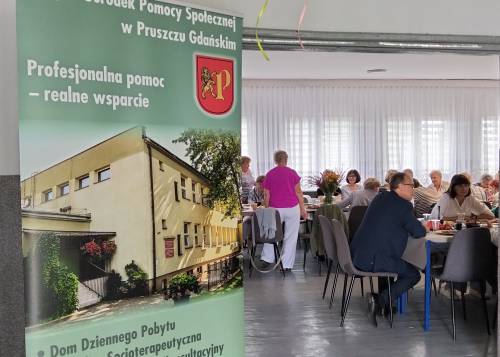 Zbliżenie na plakat i siedzących na sali seniorów