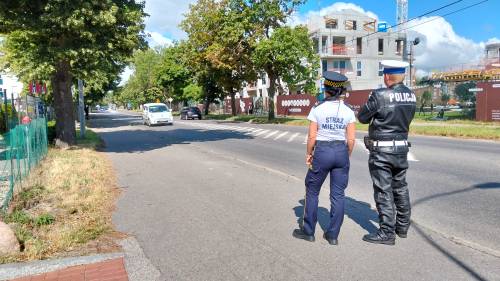 Policjant i strażniczka miejska stoją przy ulicy