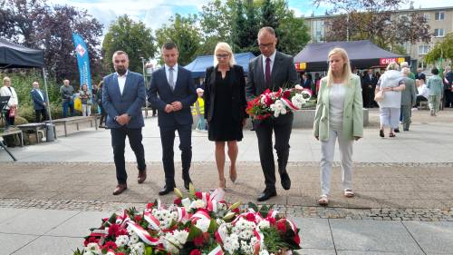 Grupa osób idzie złożyć wiązankę kwiatów