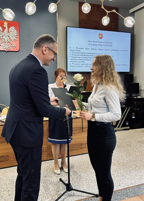 Burmistrz Pruszcza wręcza kobiecie kwiaty i dyplom