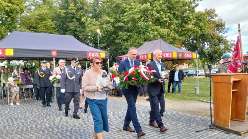 Burmistrz Pruszcza Gdańskiego, przewodnicząca rady Miasta i wiceprzewodniczący  idą ze zniczami i kwiatami