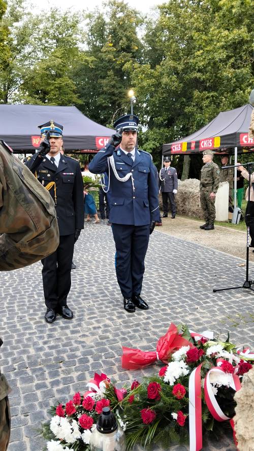 Dwóch mundurowych salutuje przed pomnikiem