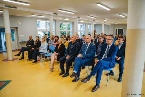 Widok na grupę osób siedzących na sali