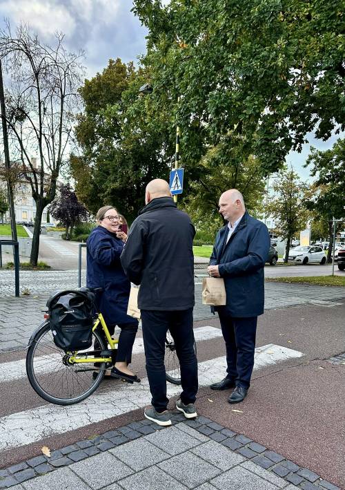 Dwóch mężczyzn stoi obok rowerzystki