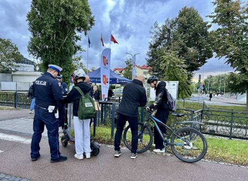 policjant stoi przy osobie z hulajnogą, obok drugi mężczyzna stoi przy rowerzyście